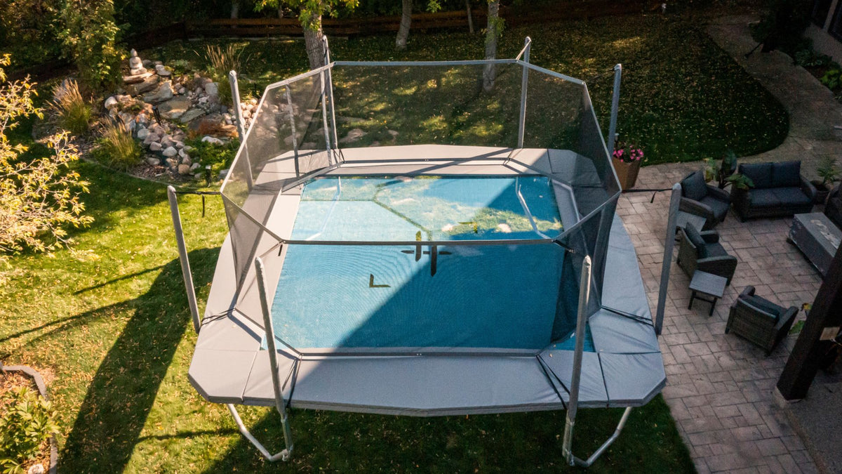 Trampoline set up in a backyard with patio furniture and landscaping.