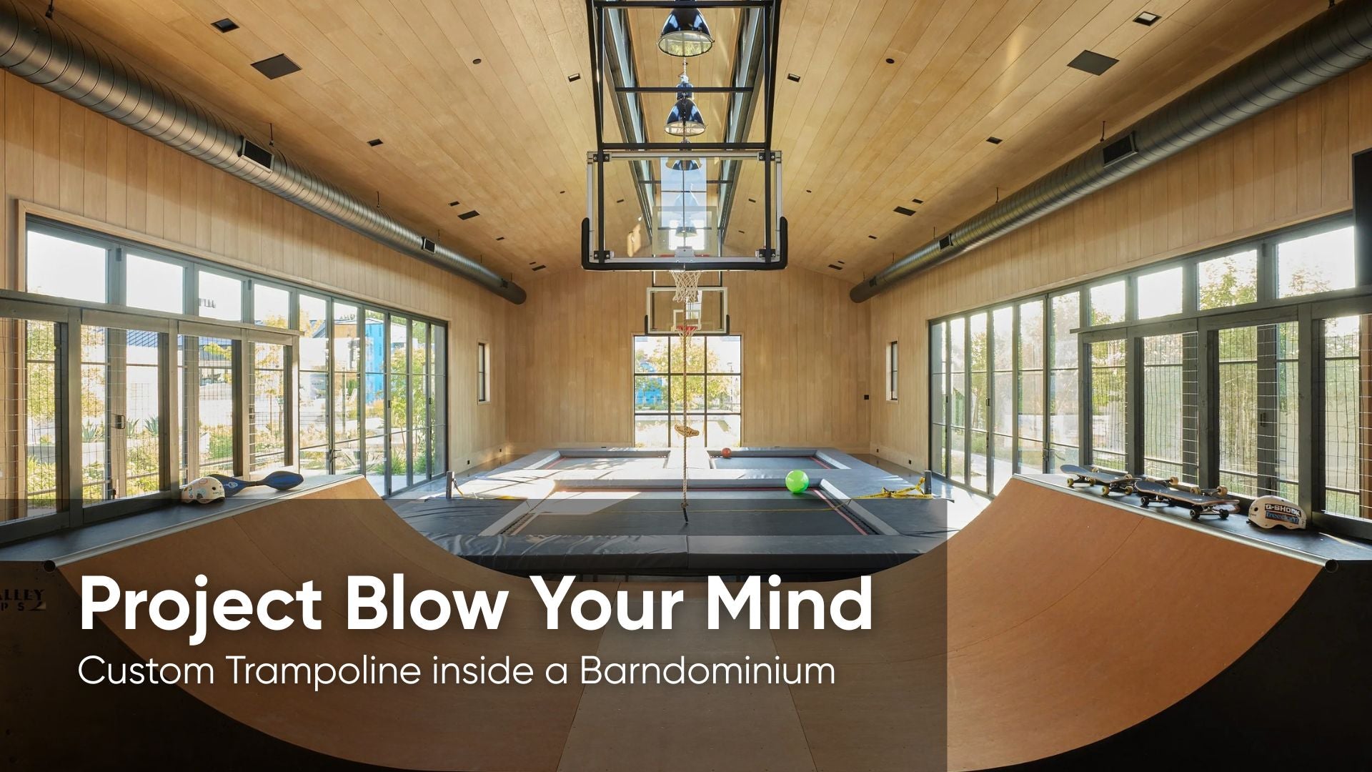 Custom trampoline inside a barndominium with large windows and wooden ceiling.