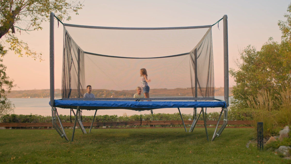 Trampoline in a backyard with people playing at sunset